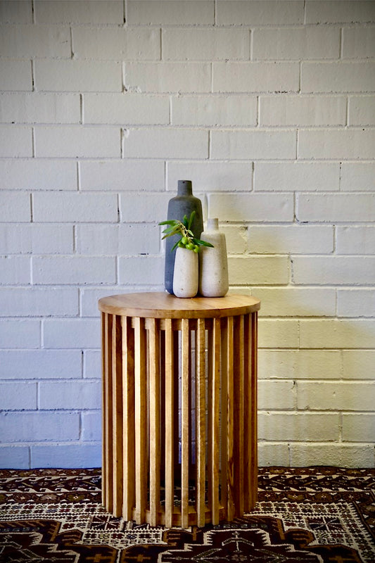 The Akashi Side Table, featuring a round top with slated sides crafted from sustainable fruitwood. Measures 400 diameter X 500 height. Styled.