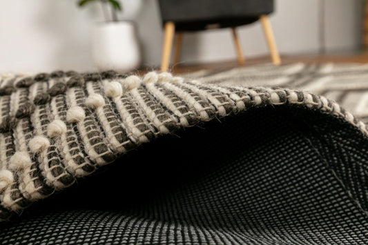 Anita Charcoal is a hand woven textured wool rug. Featuring a tribal geometric design with a 6-8mm pile height. Colour Charcoal, Grey and White. Sizes 155 X 225, 200 X 290, 240 X 320 and 300 X 400. Side.