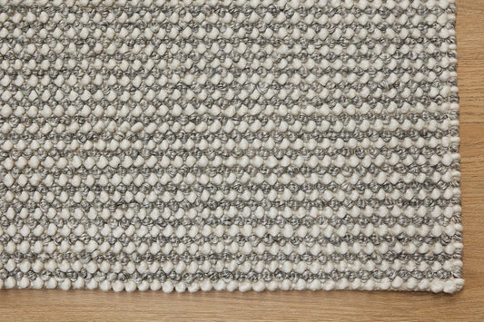 Avila - Grey is a handwoven loop piled carpet. It features a blend of fine wool and viscose, with a pile height of 16-18mm. Colours Light Grey with Dark Grey accents. Sizes 160 X 230, 200 X 290, 240 X 340 and 300 X 400. Corner.