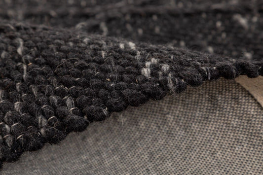 Colombo Graphite is a textured hand woven rug. Made from 80% wool and 20% polyester, it features a braided diamond pattern for an extra textured feel. Colour Black. Sizes 155 X 225, 200 X 290, 240 X 320 and 300 X 400. Side.