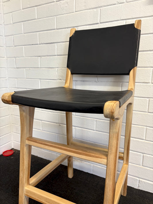 The Columbia with Back - Black Leather barstool features a black leather seat and back with sustainable teak framed legs. Colour natural teak frame with black leather seat and back. Measures 400 wide X 400 depth X 680 Seat height X 1000 Back height. Angle.