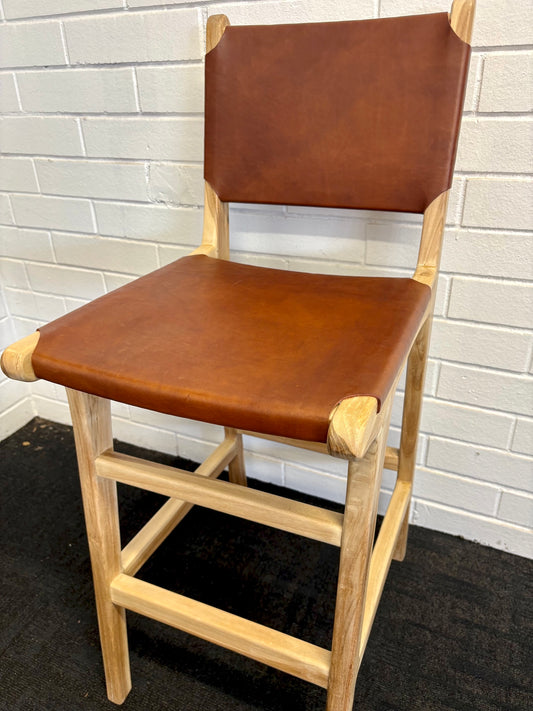 The Columbia with Back - Brown Leather barstool features a black leather seat and back with sustainable teak framed legs. Colour natural teak frame with brown leather seat and back. Measures 400 wide X 400 depth X 680 Seat height X 1000 Back height. Angle.