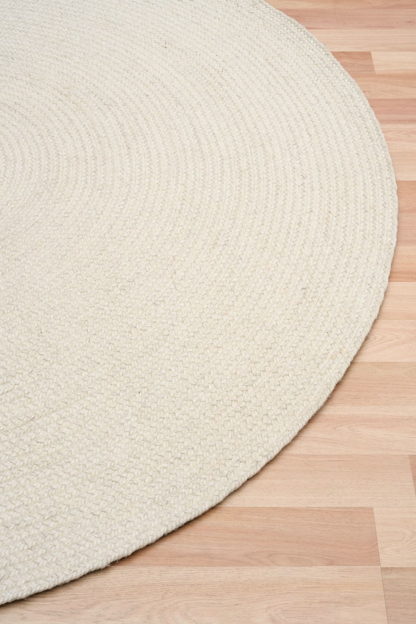 Cora Round Ivory Rug hand woven from 70% New Zealand wool and 30% viscose in a braided weave. Colour Ivory. 2 sizes, 200cm round and 250cm round. Angle View.