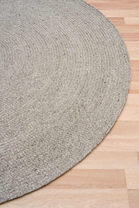 Cora Round Silver Rug hand woven from 70% New Zealand wool and 30% viscose in a braided weave. Colour Silver Grey. 2 sizes, 200cm round and 250cm round. Angle View.
