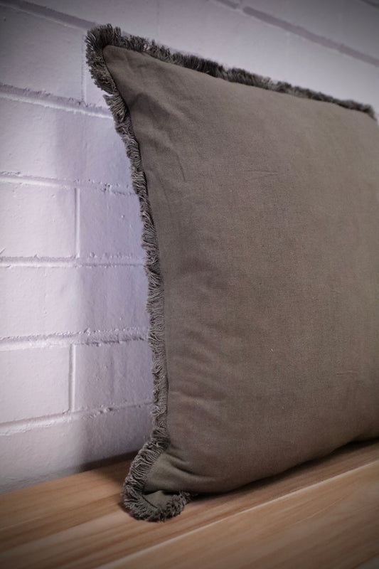 The Dusty Olive, green, throw cushion is crafted by skilled artisans in India. Made of cotton it boasts a contemporary style with a smooth luxurious cotton weave and a fringed edge. Colour green. Sizes, 50 X 50 and 60 X 60. Angle.