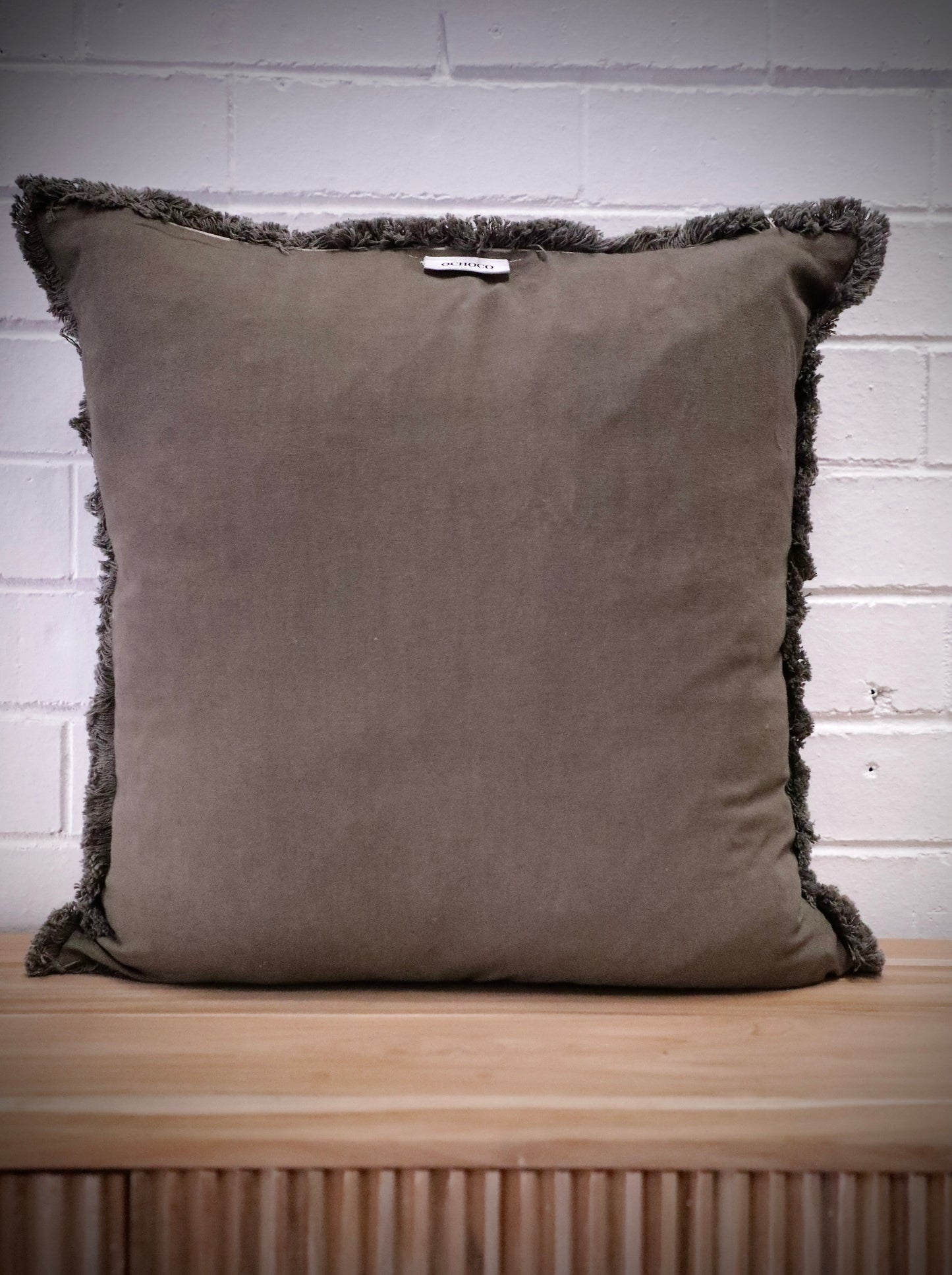 The Dusty Olive, green, throw cushion is crafted by skilled artisans in India. Made of cotton it boasts a contemporary style with a smooth luxurious cotton weave and a fringed edge. Colour green. Sizes, 50 X 50 and 60 X 60. Back.