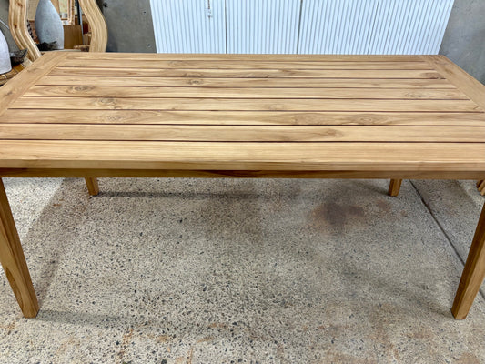 Elton indoor/outdoor dining table made from solid teak with a slatted top in a warm natural finish. Measures 1800 length x 900 width x 770 height. Wide Angle.