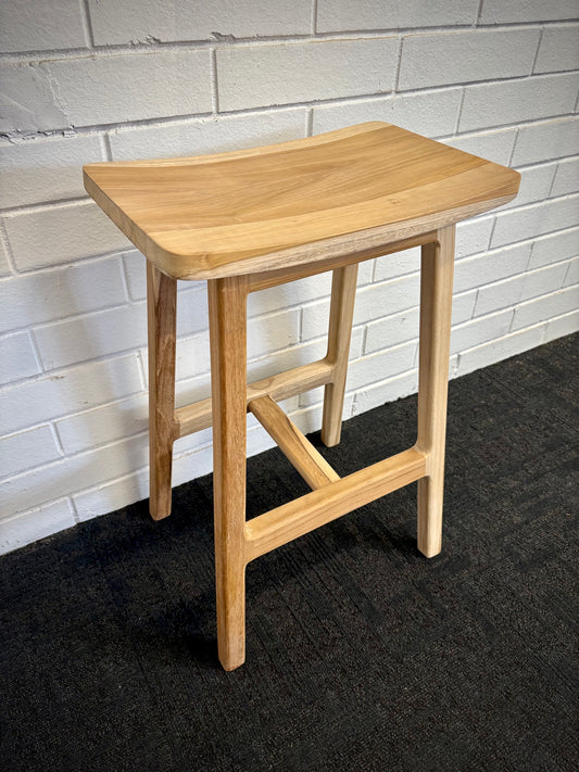 The Fitzroy Barstool features a rectangular bowed seat on A-Frame legs. Crafted from sustainable teak. Colour natural. Measures 430 wide X 300 depth X 660 height. Angle.