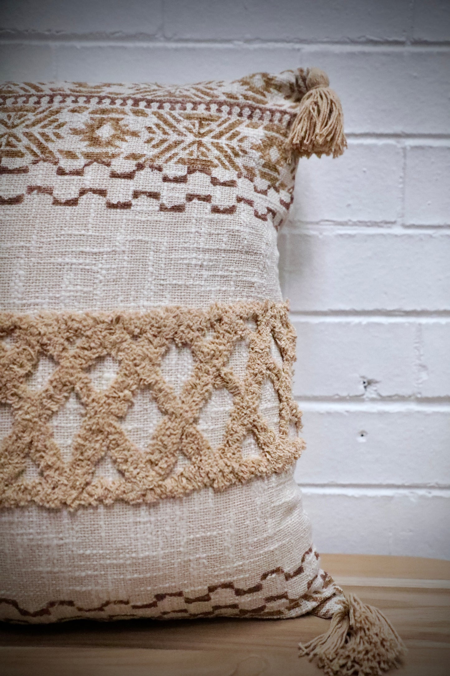The Folk Tale Throw Cushion, hand crafted in India. Made from durable soft cotton, it features geometric designs and a textured pattern with tasseled corners. Colours, beige, oranges, browns and greys. Measures 50 X 50. Front Side.