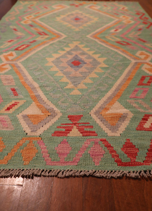 The Afghan Hand Woven Khyber Kilim - 126 X 179. Crafted using traditional vegetable dyed wool, and featuring traditional geometric designs. Colours, greens, beiges, creams, oranges. Size 126 X 179. Angle.
