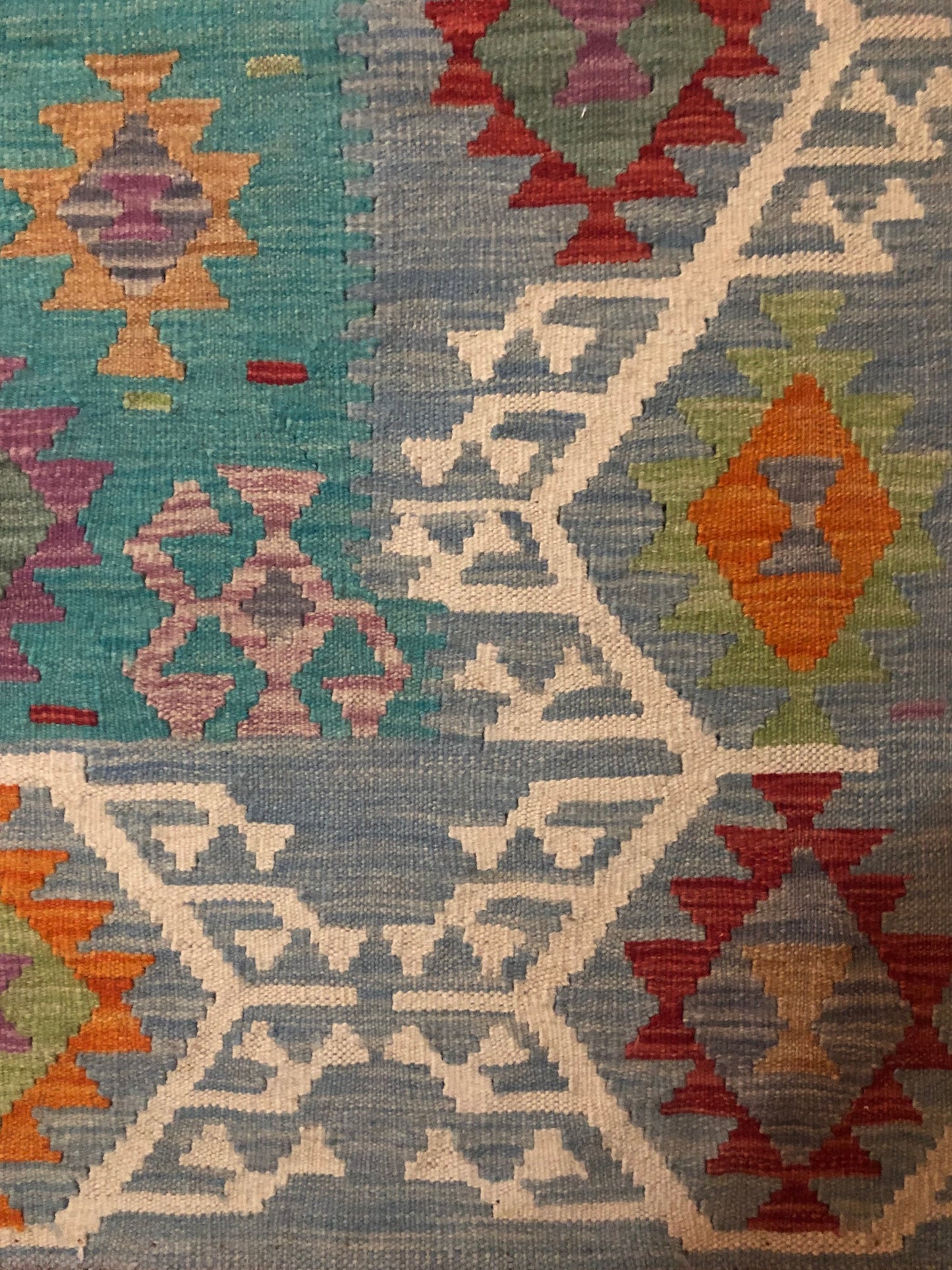 The Afghan Hand Woven Khyber Kilim - 197 X 304. Crafted using traditional vegetable dyed wool, and featuring traditional geometric designs. Colours, Greens, teals, blues, creams, reds, oranges and yellows. Size 197 X 304. Corner.