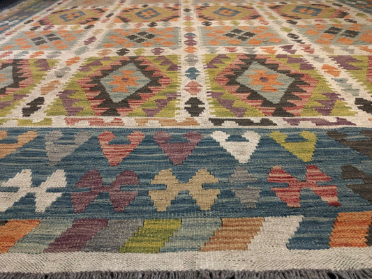 The Afghan Hand Woven Wool Khyber Kilim - 215 X 289. Crafted using traditional vegetable dyed wool, and featuring traditional geometric designs. Colours, greens, brown, cream, oranges, teals. Size 215 X 289. Angle Wide.