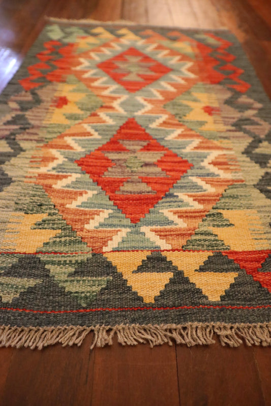 The Afghan Hand Woven Khyber Kilim - 57 X 91. Crafted using traditional vegetable dyed wool, and featuring traditional geometric designs. Colours, dark greys, beiges, blues, creams, light greens, light blues and yellows. Size 57 X 91. Angle.