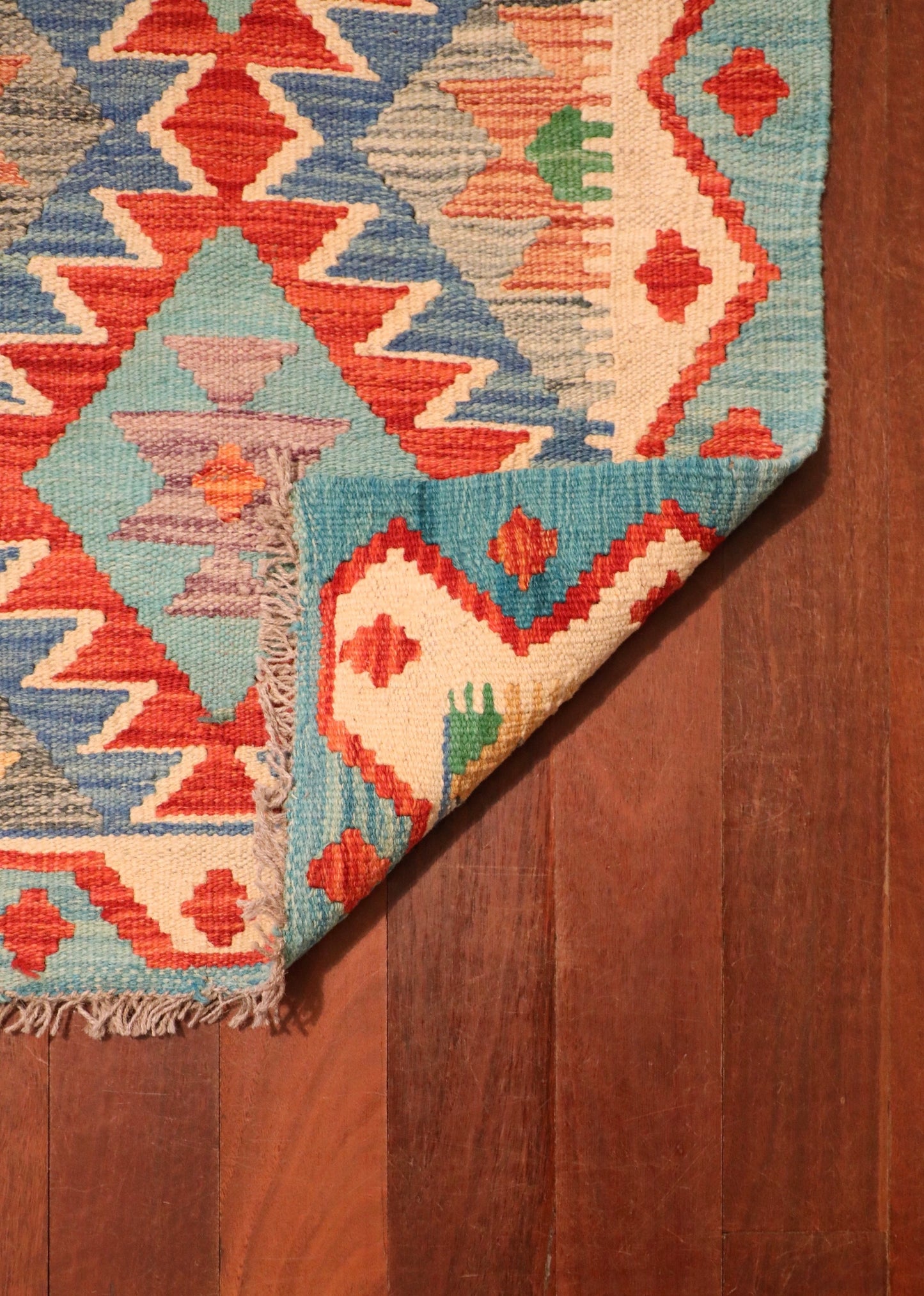 The Afghan Hand Woven Khyber Kilim - 58 X 88. Crafted using traditional vegetable dyed wool, and featuring traditional geometric designs. Colours, Dark oranges, creams, light greens, light blues yellows. Size 58 X 88. Fold.
