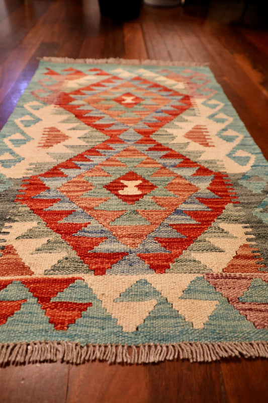 The Afghan Hand Woven Khyber Kilim - 59 X 88. Crafted using traditional vegetable dyed wool, and featuring traditional geometric designs. Colours, oranges, creams, light greens, light blues. Size 59 X 88. Angle.