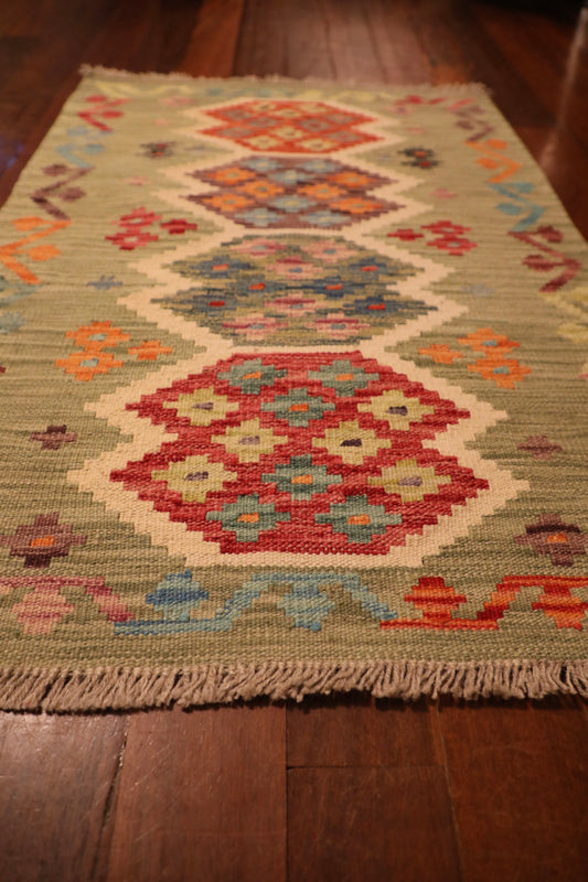 The Afghan Hand Woven Khyber Kilim - 65 X 92. Crafted using traditional vegetable dyed wool, and featuring traditional geometric designs. Colours, light greens, light blues, reds, beiges, creams, oranges and yellows. Size 65 X 92. Angle.