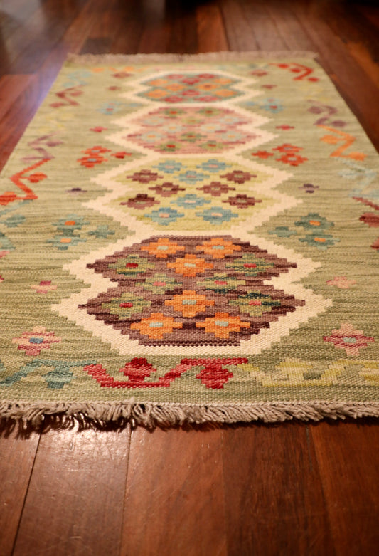 The Afghan Hand Woven Khyber Kilim - 67 X 94. Crafted using traditional vegetable dyed wool, and featuring traditional geometric designs. Colours, light greens, creams, light blues, reds and orange. Size 67 X 94. Angle.