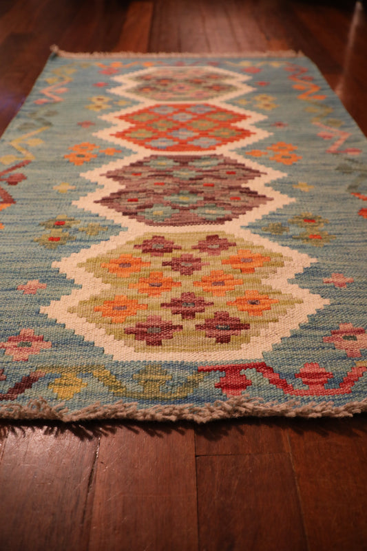 The Afghan Hand Woven Khyber Kilim - 68 X 92. Crafted using traditional vegetable dyed wool, and featuring traditional geometric designs. Colours, teal green, light blues, reds, beiges, creams, oranges and yellows. Size 68 X 92. Angle.