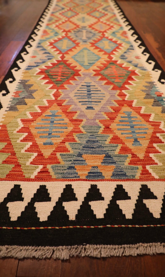 The Afghan Hand Woven Khyber Kilim Runner - 79 X 293. Crafted using traditional vegetable dyed wool, and featuring traditional geometric designs. Colours, dark blue, creams, beiges, oranges, light greens and more. Measures 79 wide X 293 long. Angle.