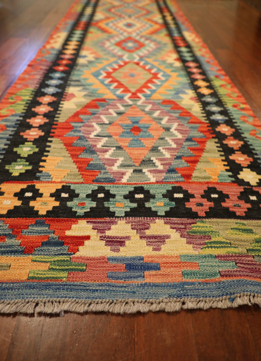 The Afghan Hand Woven Khyber Kilim Runner - 80 X 295. Crafted using traditional vegetable dyed wool, and featuring traditional geometric designs. Colours, ,Oranges, blues, creams, reds, yellows, aqua and more. Measures 80 wide X 295 long. Angle.