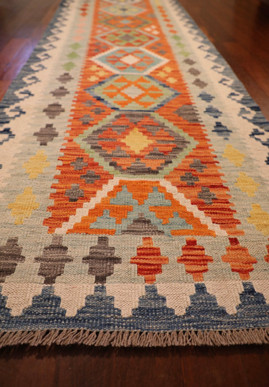 The Afghan Hand Woven Khyber Kilim Runner - 82 X 283. Crafted using traditional vegetable dyed wool, and featuring traditional geometric designs. Colours, blues, yellows, creams, beiges, oranges and more. Measures 82 wide X 283 long. Angle.