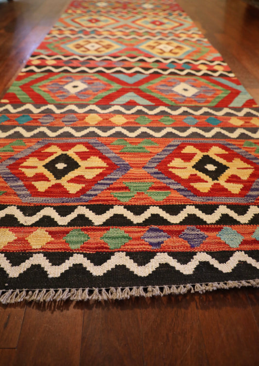 The Afghan Hand Woven Khyber Kilim Runner - 84 X 300. Crafted using traditional vegetable dyed wool, and featuring traditional geometric designs. Colours, reds, yellows, creams, beiges, oranges, light greens and more. Measures 84 wide X 300 long. Angle.