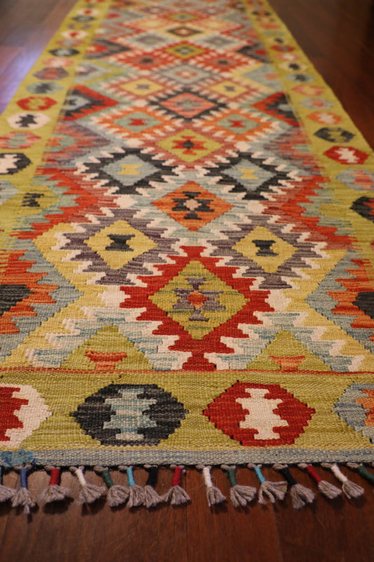The Afghan Hand Woven Khyber Kilim Runner - 86 X 290. Crafted using traditional vegetable dyed wool, and featuring traditional geometric designs. Colours, yellows, creams, beiges, oranges, blues and more. Measures 86 wide X 290 long. Angle.