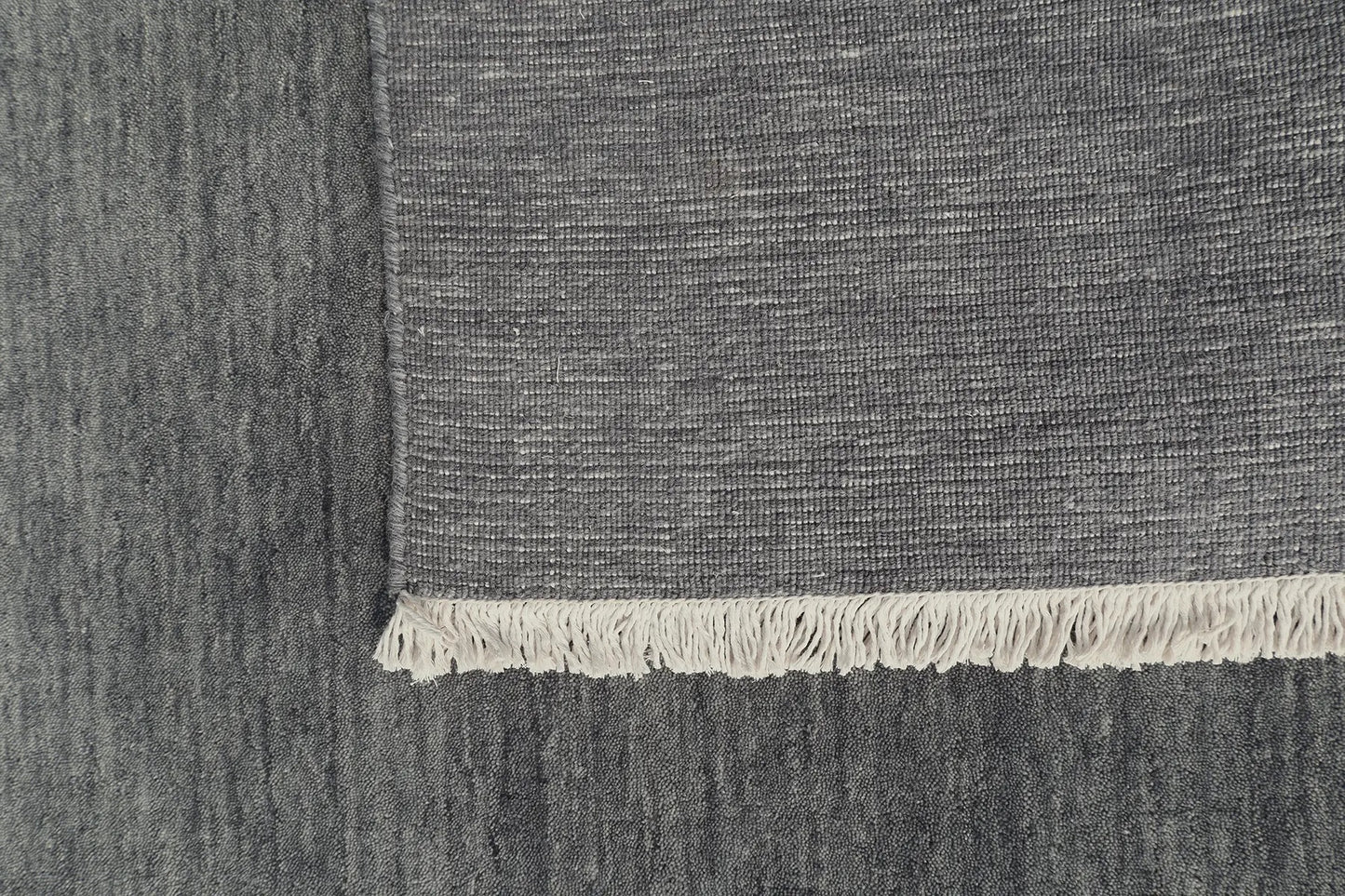 Lori Smoke is a luxurious hand loomed floor rug made of 100% wool. The wool material creates a soft texture and a smooth pile height of 16-18mm. Colour dark smokey Grey with cream tassels. Sizes 160 X 230, 200 X 290, 240 X 340 and 300 X 400. Fold.