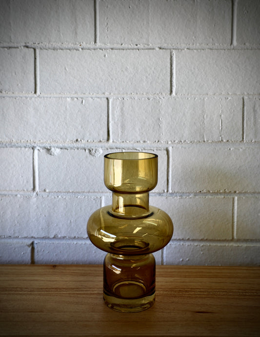 The Marte Glass Vase is a modern/contemporary piece. Featuring a cylindrical Bottom and top with a bulbed middle. Colour Amber. Measures 13 Diameter X 20 Height. Plain.