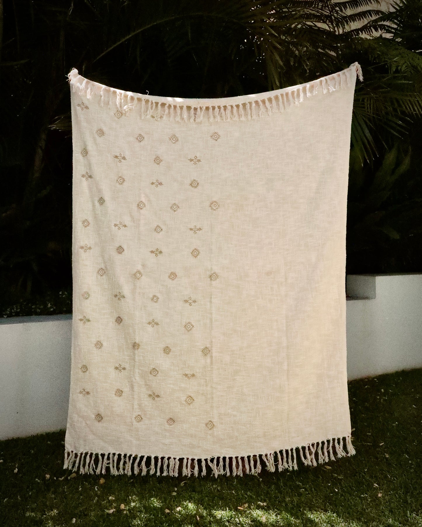 The Moroccon embroidered cotton slub throw blanket. With embroidered tassels and a modern twist on the geometric artwork. Crafted by skilled artisans in India. Colours, cream, white and brown motifs. Size 130 X 170. Styled.