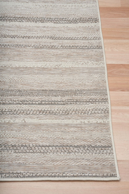 The Patio Linen 900 indoor/outdoor rug featuring neutral tones and a subtle textured pattern, power-loomed from UV-stabilised polypropylene for lasting durability. Colours, Linen, Beiges and hints of black. 3 sizes. Corner.