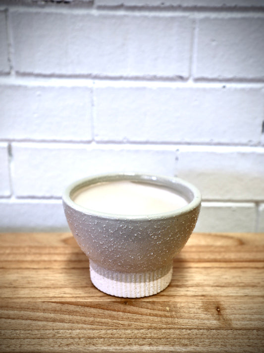 The Romulus Ceramic Pot - Small, 14 X 10, features a cylindrical bottom that tapers out in a bowl shape. Colours, cream and beige. Measures 14 Diameter X 10 Height. Plain.