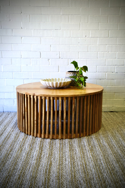 The Seger Natural Coffee Table features solid round top and slatted sides. Crafted from sustainable fruitwood. Colour natural. Measures 900 diameter X 400 height. Front Styled.