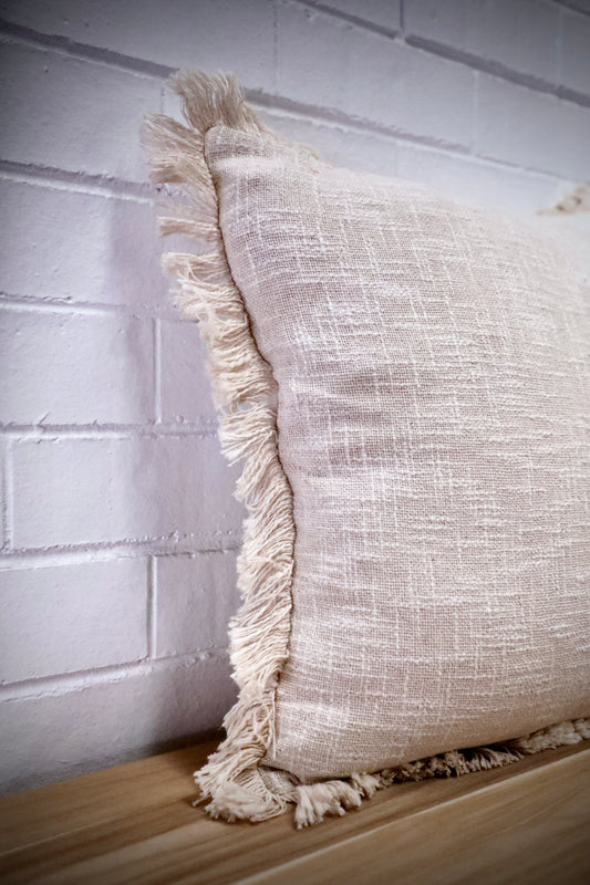 The Sun Baked - Cloud, throw cushion is made by skilled artisan weavers in India. Crafted from cotton slub, it features a luxurious textured feel. Boasts tasseled edges. Colour White. Size 50 X 50. Angle.
