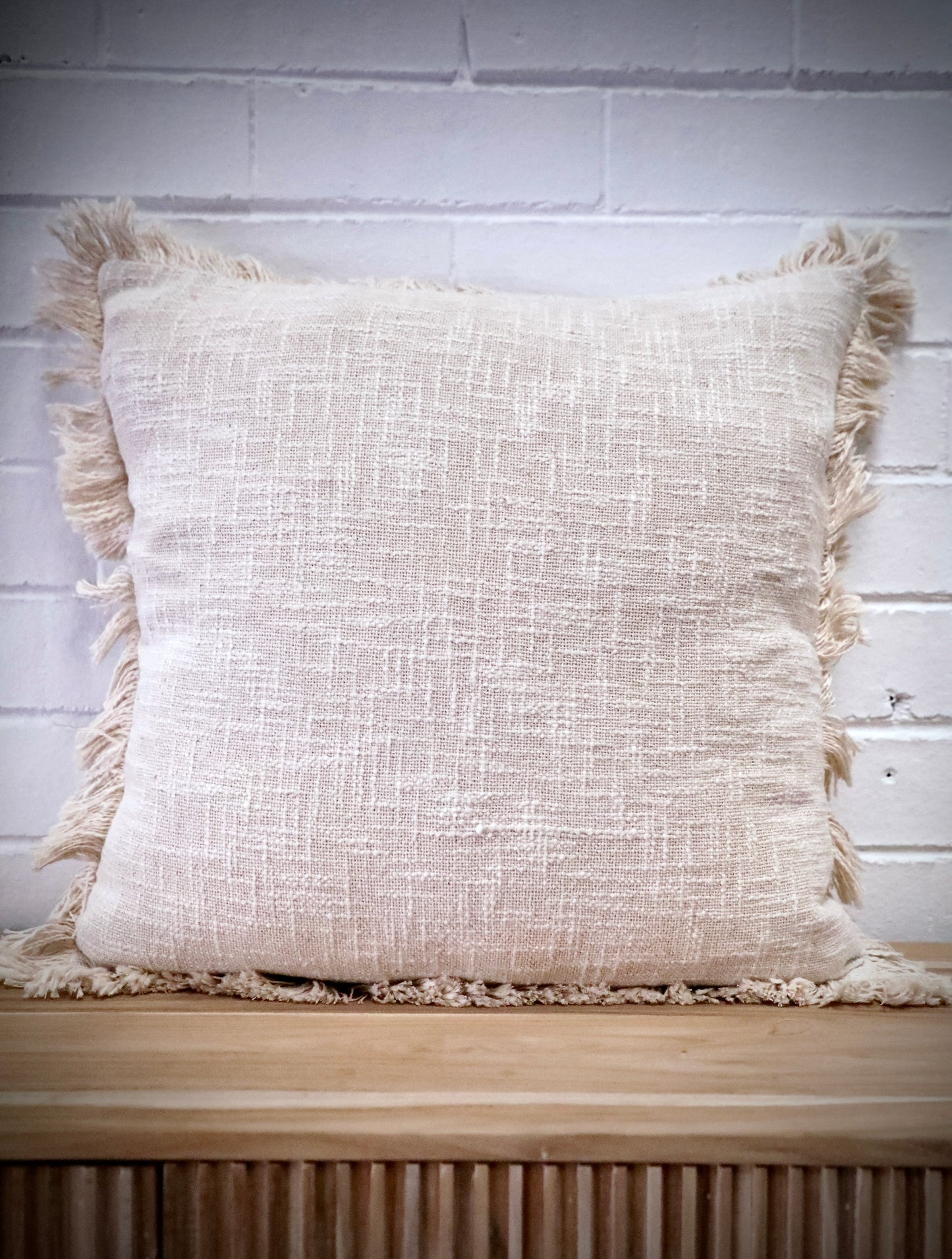 The Sun Baked - Cloud, throw cushion is made by skilled artisan weavers in India. Crafted from cotton slub, it features a luxurious textured feel. Boasts tasseled edges. Colour White. Size 50 X 50. Front.