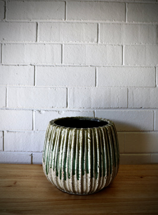 The Varuna Ceramic Pot - Medium, features a textured ribbed outer shell. Great for small plants. Colour, Olive and Teal. Size 23 Diameter X 18 Height. Plain.