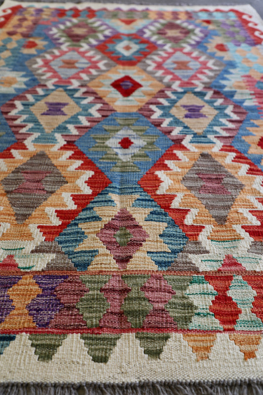 The Afghan Khyber Kilim - 126 X 178. Crafted using traditional vegetable dyed wool, and featuring traditional geometric designs. Colours, Beige, blue, red, yellow brown. Size 126 X 178. Angle.
