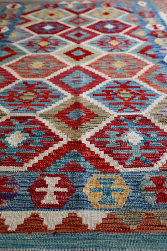 The Afghan Hand Woven Khyber Kilim - 129 X 178. Crafted using traditional vegetable dyed wool, and featuring traditional geometric designs. Colours, brown, red, blue, cream, teal. Size 129 X 178. Angle.