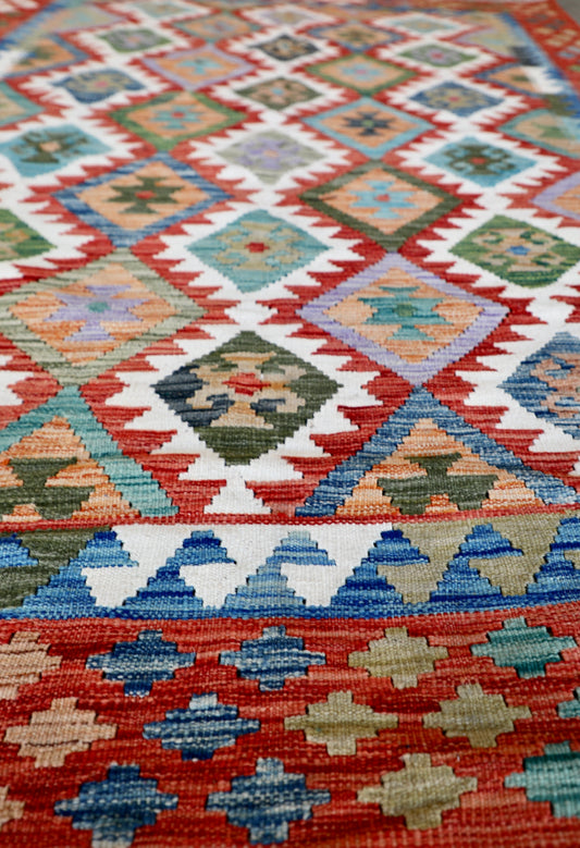 The Afghan Hand Woven Khyber Kilim - 172 X 250. Crafted using traditional vegetable dyed wool, and featuring traditional geometric designs. Colours, cream, reds, greens, blues, oranges. Size 172 X 250. Angle.