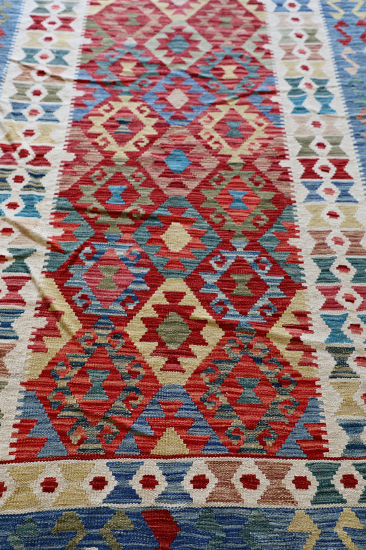The Afghan Hand Woven Khyber Kilim - 180 X 248. Crafted using traditional vegetable dyed wool, and featuring traditional geometric designs. Colours, cream, blues, greens, reds, oranges. Size 180 X 248. Angle.