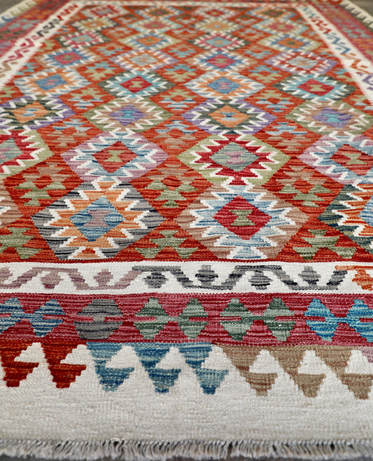The Afghan Hand Woven Wool Khyber Kilim - 206 X 296. Crafted using traditional vegetable dyed wool, and featuring traditional geometric designs. Colours, cream, reds, oranges, teals, blues and beiges. Size 206 X 296. Angle.