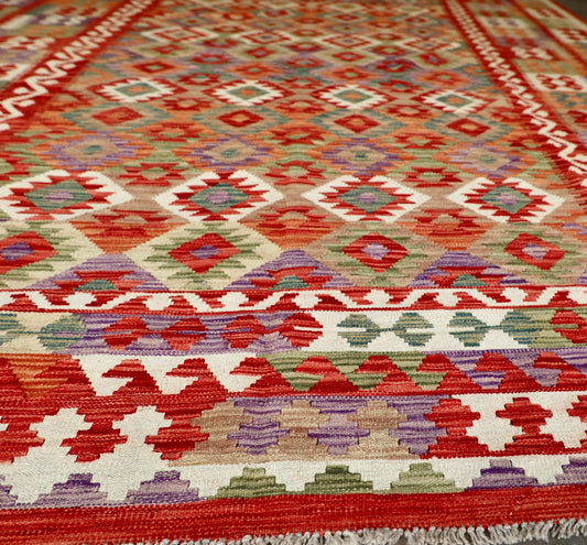 The Afghan Hand Woven Khyber Kilim - 252 X 345. Crafted using traditional vegetable dyed wool, and featuring traditional geometric designs. Colours, Oranges, reds, creams, teals. Size 252 X 345. Angle.