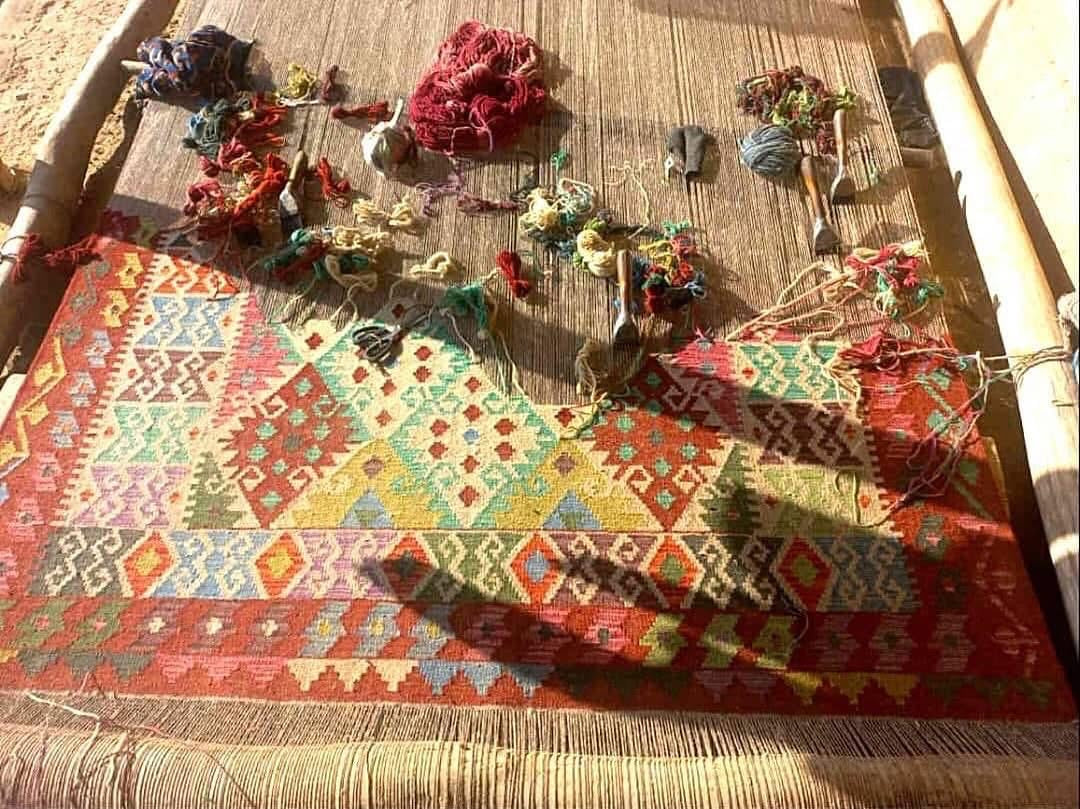A hand woven Khyber Kilim rug being hand woven on a traditional loom.