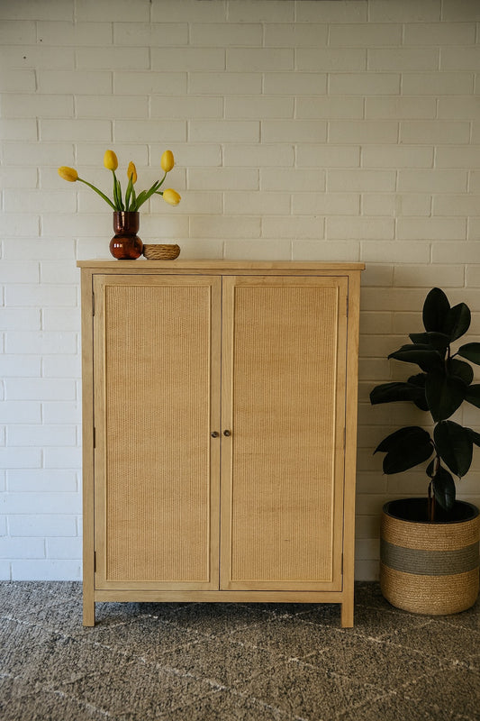 Aquarius 2 Door Cabinet. A refined storage solution designed for contemporary living. Crafted from Solid white cedar with a close rattan mesh door front. Colour Natural. Measures 1000 wide x 1400 height x 400 Depth. Styled.