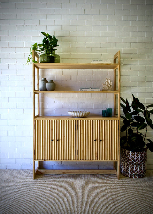 The Aquarius 4 Door Bookshelf, featuring a coastal/contemporary design. With 3 shelves and 4 textured doors which open to an additional inner shelf. Crafted from sustainable white cedar. Colour Natural. Measures 1180 Wide x 400 Depth x 1850 Height. Front Styled.