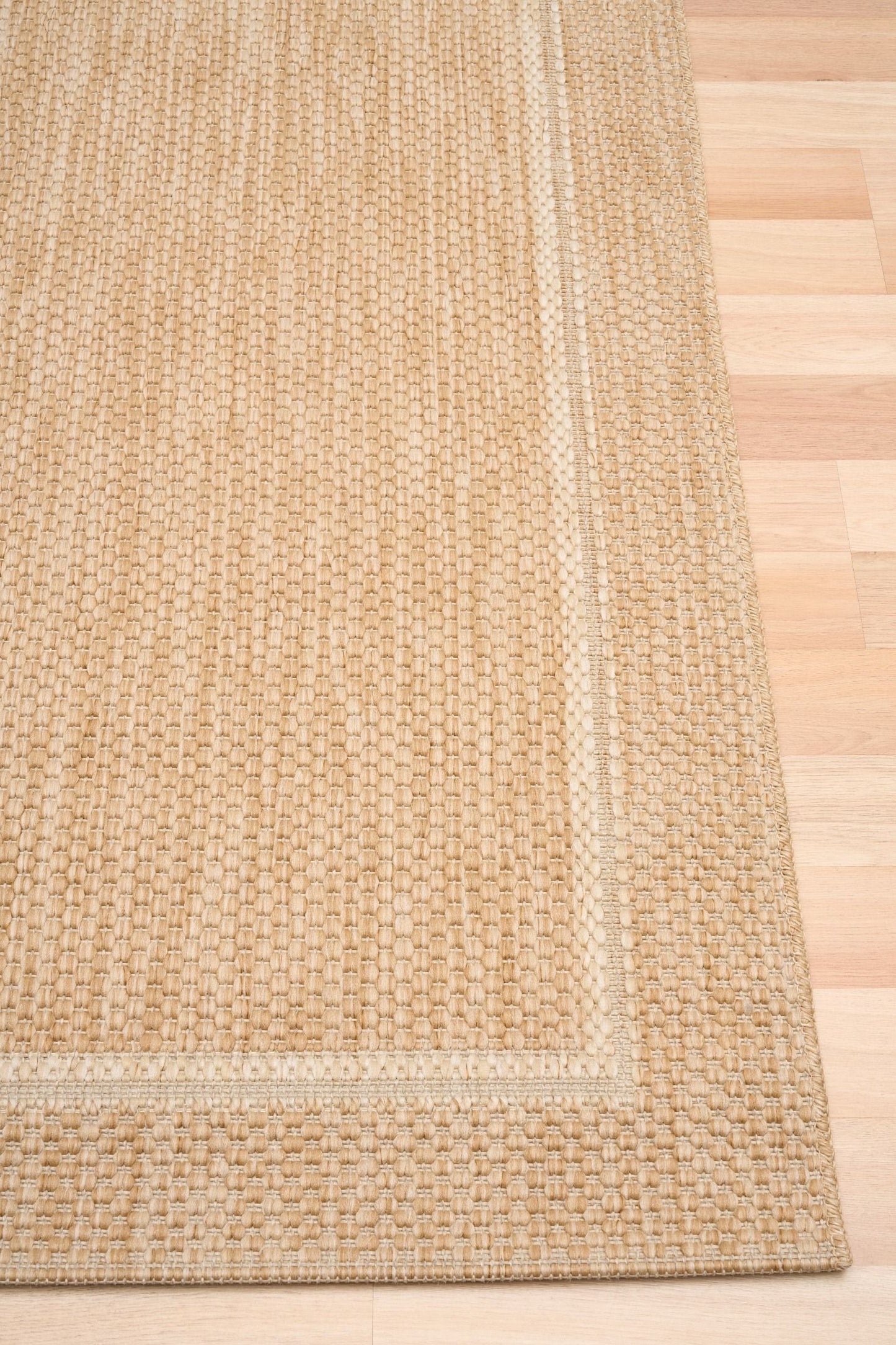 Barton Border Beige indoor/outdoor rug featuring soft beige tones and a subtle textured pattern, power-loomed from UV-stabilised polypropylene for lasting durability. Colour Beige. 3 sizes. Corner.