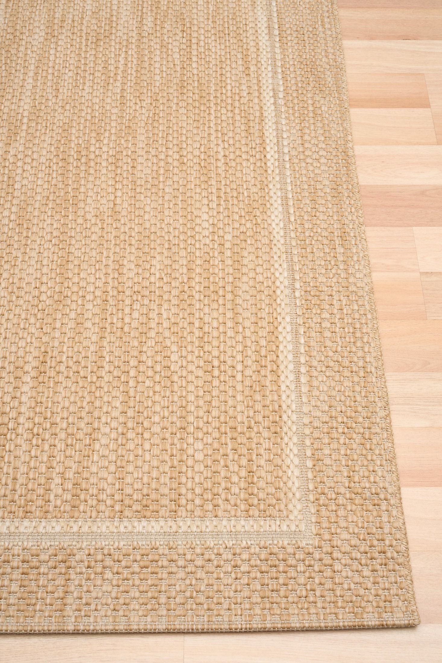 Barton Border Beige indoor/outdoor rug featuring soft beige tones and a subtle textured pattern, power-loomed from UV-stabilised polypropylene for lasting durability. Colour Beige. 3 sizes. Corner.