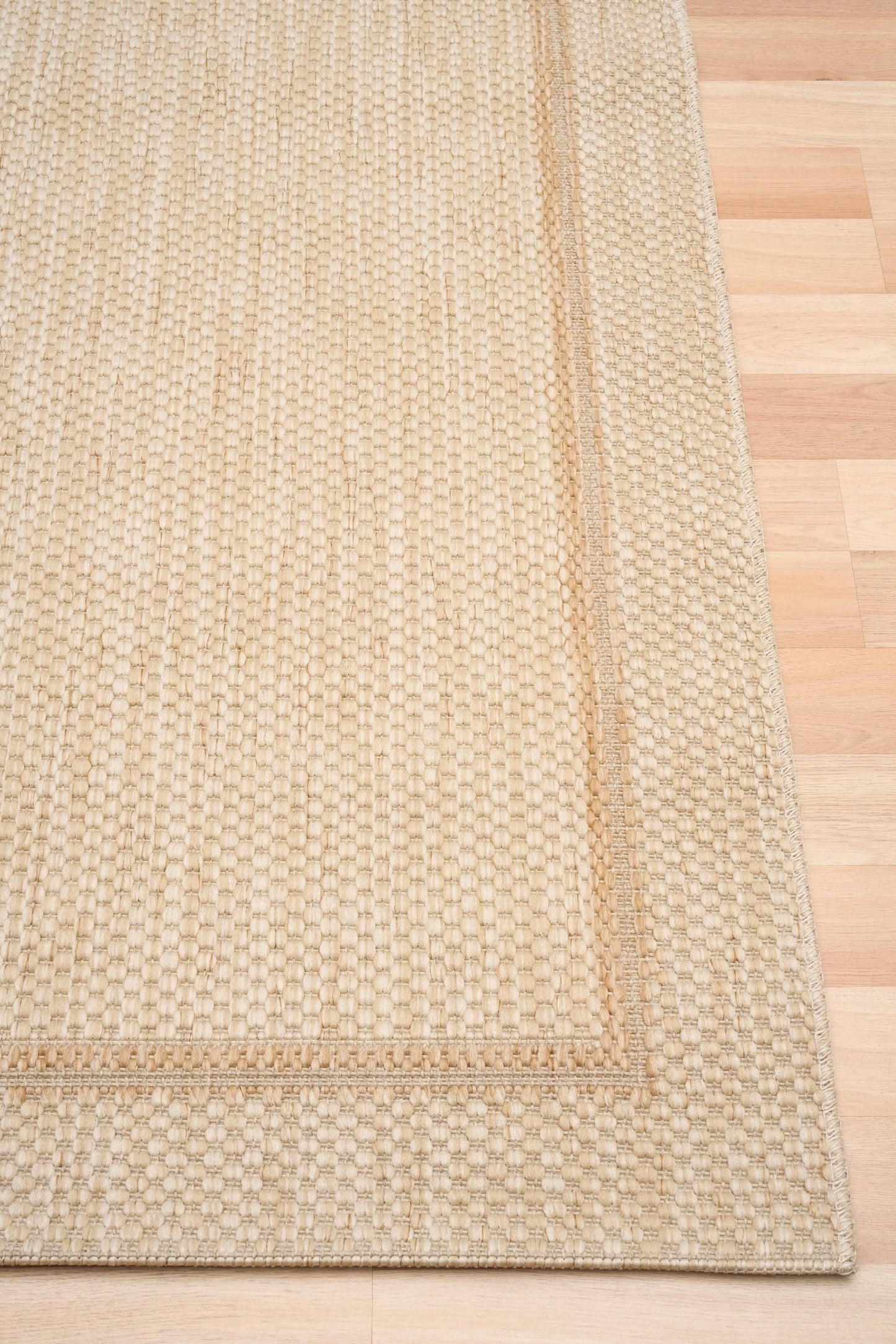 Barton Border Cream indoor/outdoor rug featuring soft cream tones and a subtle textured pattern, power-loomed from UV-stabilised polypropylene for lasting durability. Colour Cream. 3 sizes. Corner.