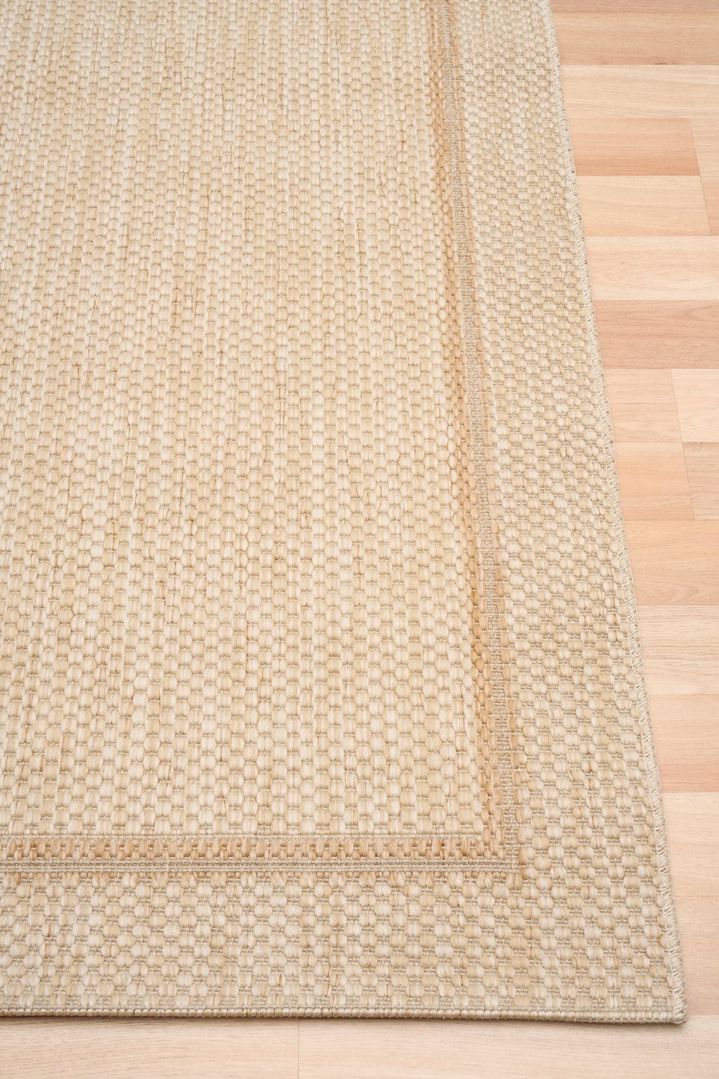 Barton Border Cream indoor/outdoor rug featuring soft cream tones and a subtle textured pattern, power-loomed from UV-stabilised polypropylene for lasting durability. Colour Cream. 3 sizes. Corner.