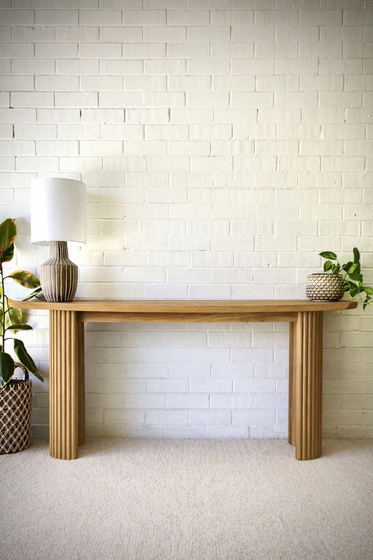 Berlin Teak Top Console crafted from solid teak. Featuring solid teak top with rounded ends and solid fluted pillar supports. Colour Natural Teak. Measures 1600 Wide X 350 Depth X 7500 Height. Styled.
